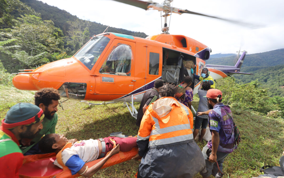 Tommy Gat (in the stretcher) being carried by his fellow villagers to the helicopter.